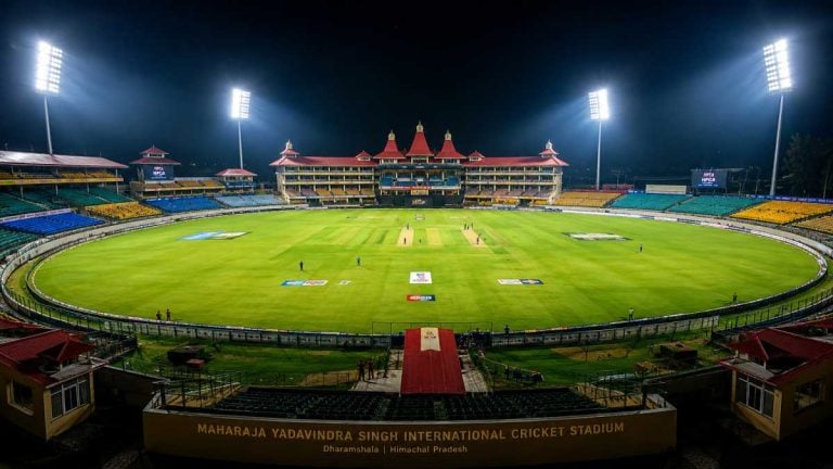 Dramatic floodlit view of Maharaja Yadavindra Singh International Cricket Stadium during IPL 2026 Qualifier 2 with glowing Scorpio Moon and planetary alignments overhead, Rajasthan Royals players in celebration mode amid packed stands.